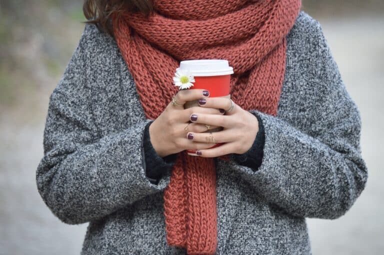 Woman wearing a warm scarf holding coffee